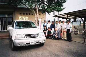 野殿セキュリティープロジェクトの皆さんが防犯パトロールカーの脇に集合しています